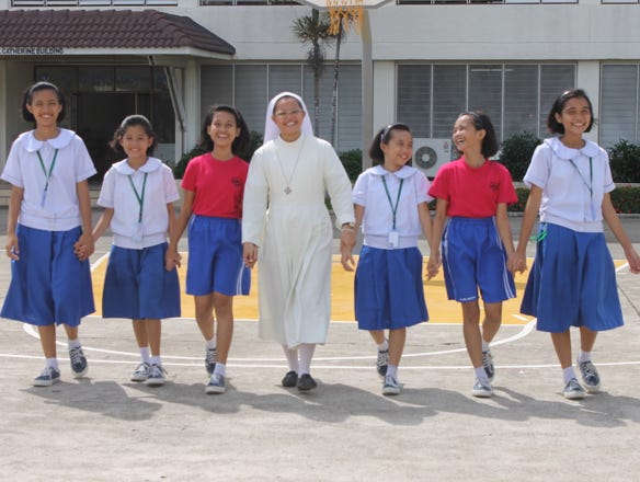A sister of the "Sisters of Mary" order with young girls holding each others hands